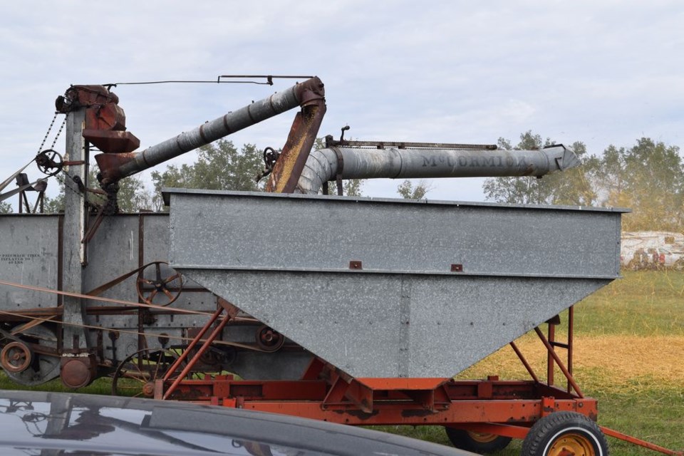 Grain flowed from the threshing machine into the wagon while the straw was fed out the back end. 