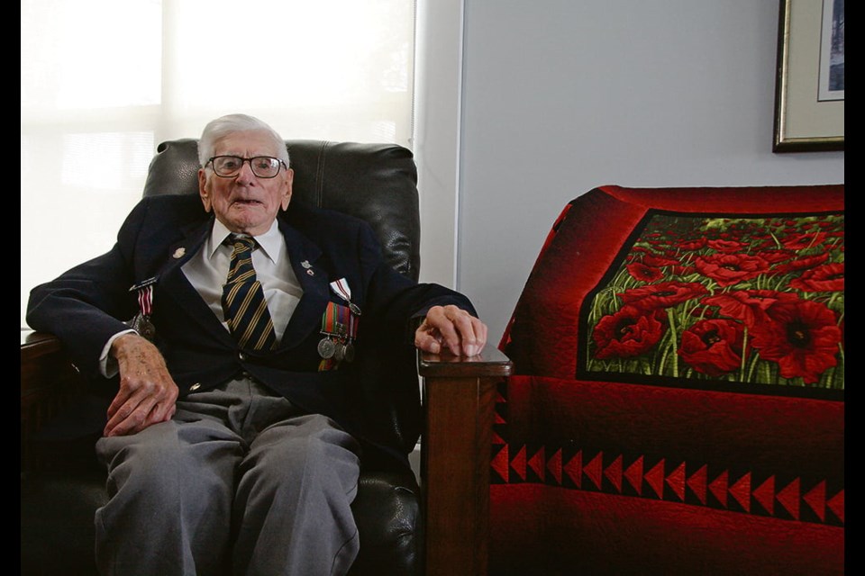 Second World War veteran Tracy Cross, wearing his service medals, sits beside the poppy quilt made for him by Linda Hanline, who works at Cypress Lodge in Maple Creek, Sask., where he now lives. | 