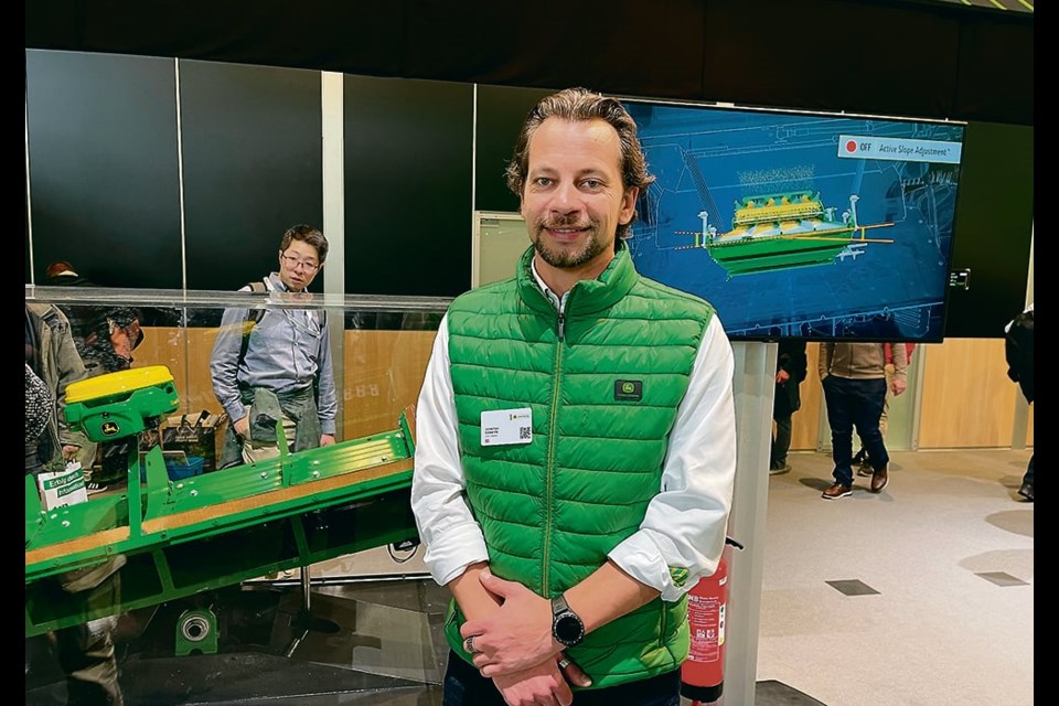 John Deere’s Jonathan Edwards stands in front of the company’s new Active Slope Adjustment for combine cleaning shoes at Agritechnica. 