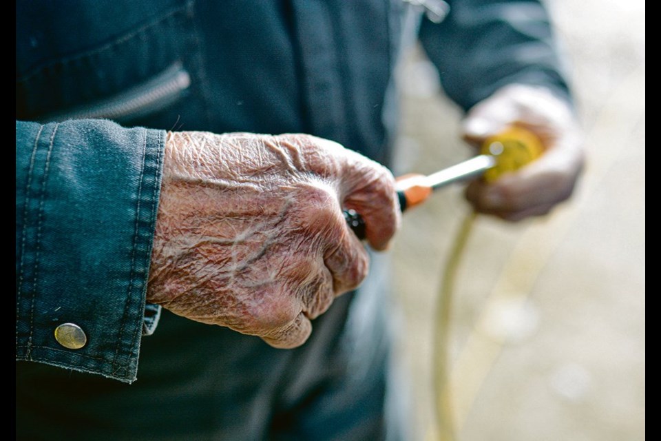 Cattle producer William (Bill) Edgar Fruson handles a screwdriver while putting on a new grounding plug for an extension cord.