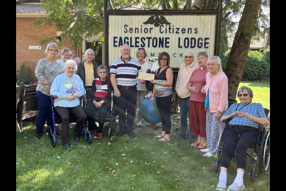Rick Aikman, the warden of the Anglican Church, presented a cheque for $10,000 to Tricia Seppak the Manager of Eaglestone Lodge of Kamsack, surrounded by parishioners and residents of the Lodge. 