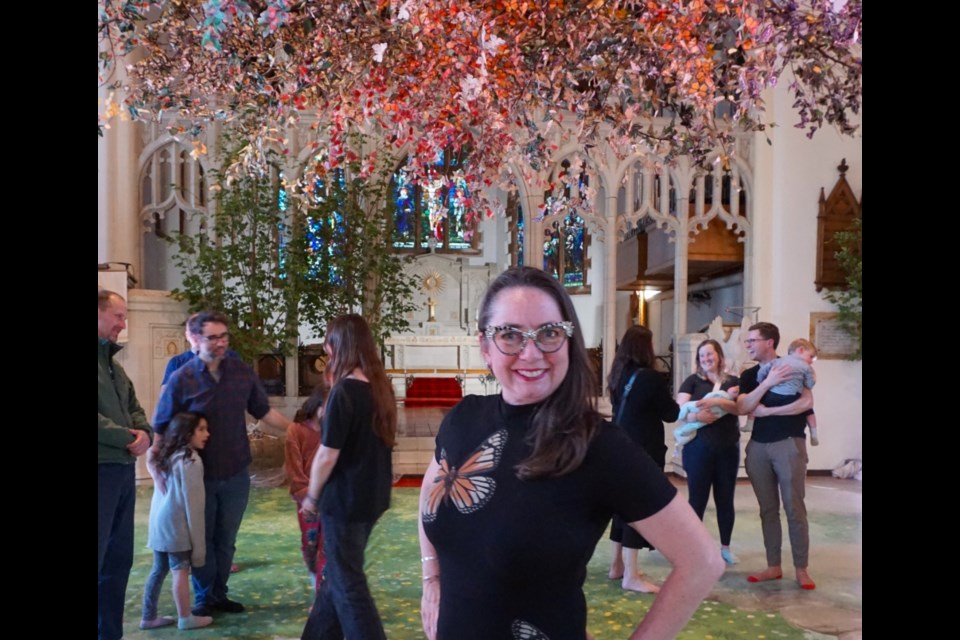 Monique Martin poses with the thousands of butterflies she painstakingly made to complete her Metamorphosis exhibit.