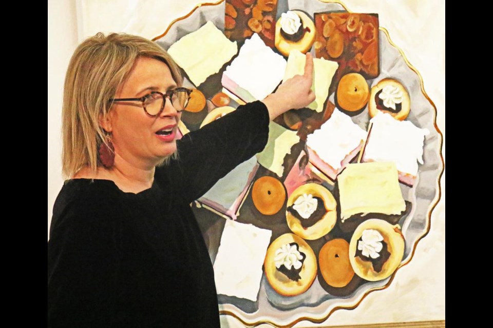 Artist Sarah Cummings Traszkowski points out items in her painting of a dish of Christmas goodies, from her exhibit at the Weyburn Art Gallery.
