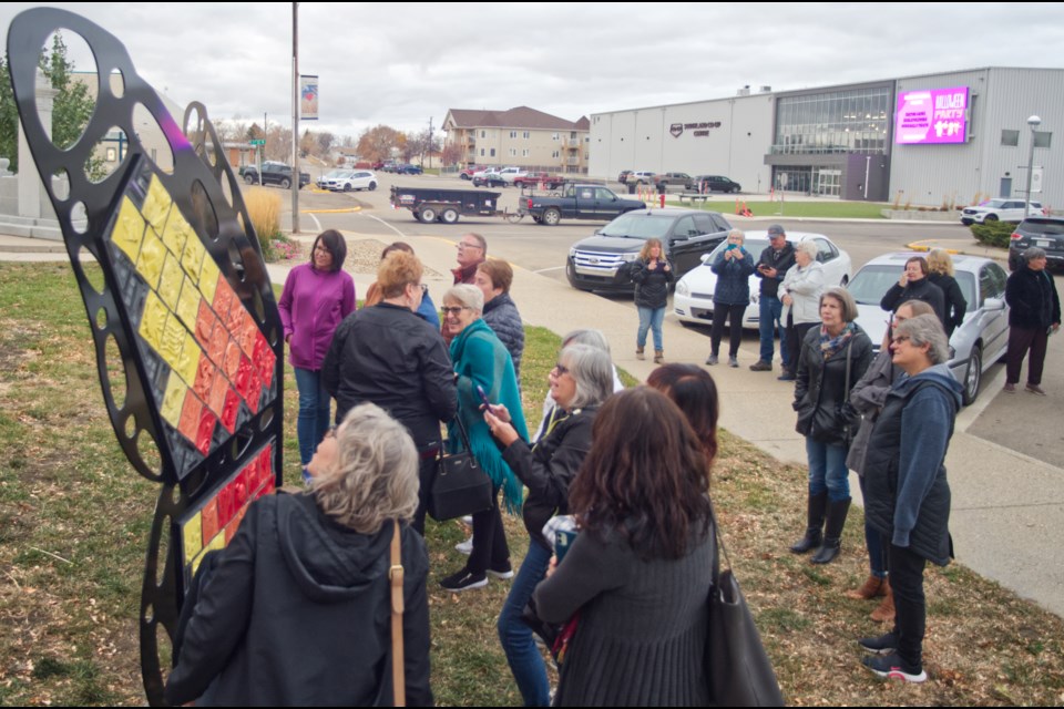 Community members art contributing artists take a closer look at almost 100 tiles involved in the creation of the Metamorphosis project.