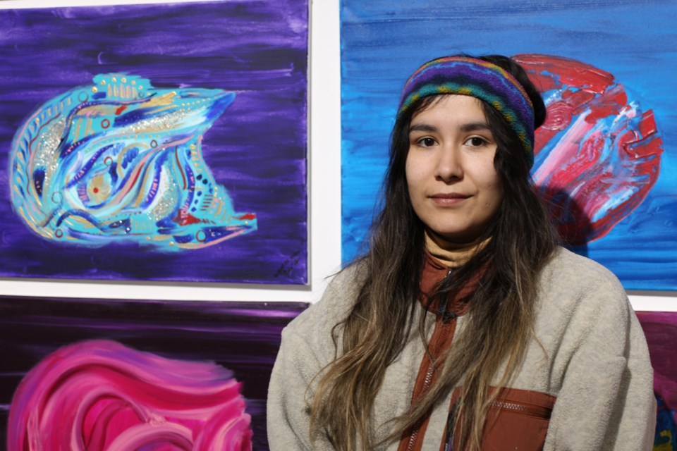 Gabrielle Fourstar, pictured here next to their works at the GDAG.