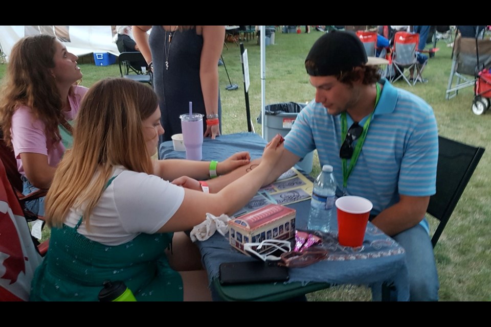 Mariah Warriner, left, gave a henna tattoo to Carter Vosper, who is one of the band members of The Blu Beach band.