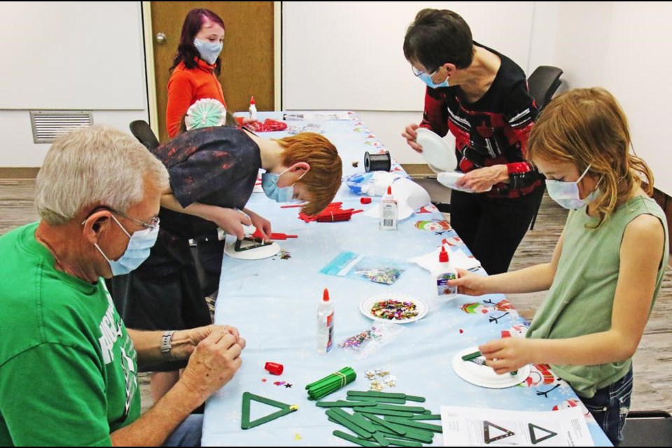 This was a busy table for Christmas craft-making on Wednesday, with Bob Klemmer at left, Cody and Elizabeth Wig, and library board chair Diane Sander at right. This was part of the Weyburn Library's Cards, Crafts and Carols evening on Wednesday.