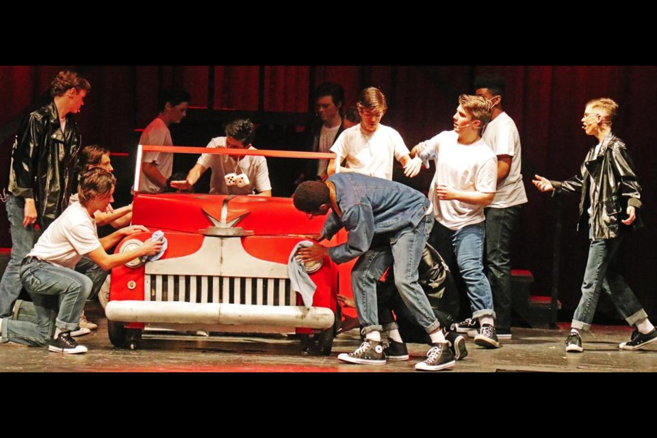 The guys in the gang polish up Kenickie's ride, in a scene from "Grease", being staged at the Cugnet Centre