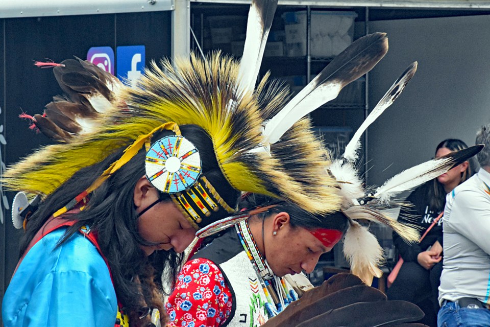 Two Indigenous dancers are deep in thought as one of their Elders delivers the opening prayer.