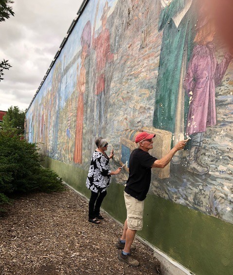 Original artist Grant McLaughlin from Moose Jaw, and local artist Tonia Vermette prepare the mural for its touch-ups.