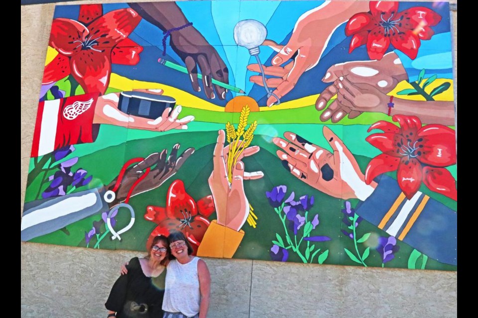 With cries of "It's done!", Tasha Hill and Regan Lanning of the Weyburn Arts Council happily posed in front of the large mural which was installed on Friday afternoon in downtown Weyburn, three years after the journey began.