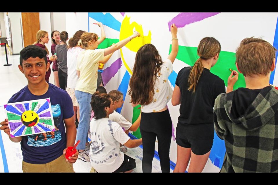 Haroun, a Grade 8 student at St. Michael, shows his prize-winning painting, which his classmates are painting behind him on the wall outside of the Weyburn Art Gallery on Wednesday afternoon.