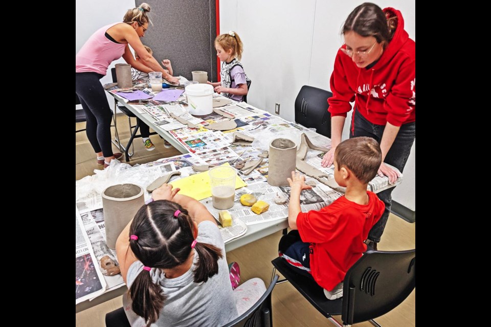 Brittni Skjerdal helped her children, Jake and Sophie, to make a clay vase, while Zoe Molder (at right) helped out Alexander and Alyssa Bull with their projects, during the pottery class on Saturday afternoon