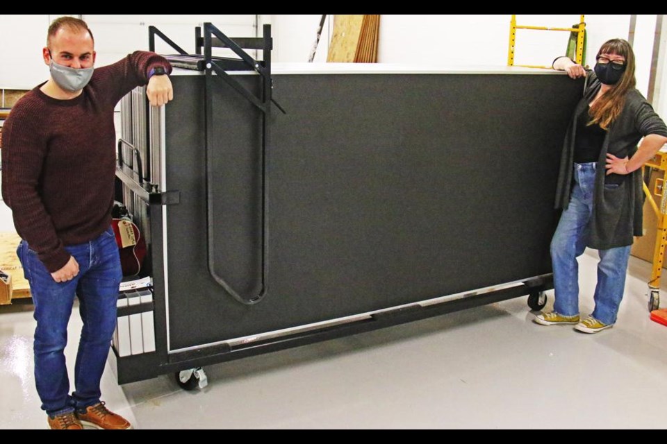 Ryan Dale, leisure services manager for the Spark Centre, and Regan Lanning, arts program coordinator, show how compact and mobile the new stage is when it's folded up on its trolley. A grant from the Helen Davidson Foundation made the purchase of this stage possible.
