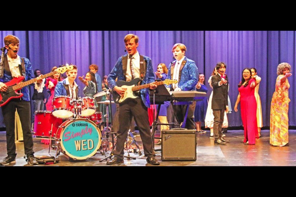 The wedding band plays at a wedding reception, fronted by Robbie (Liam Evans), and bandmates Sammy and George (Jonas Burdan, left, and Alex Paszkiewicz) in 'The Wedding Singer'.