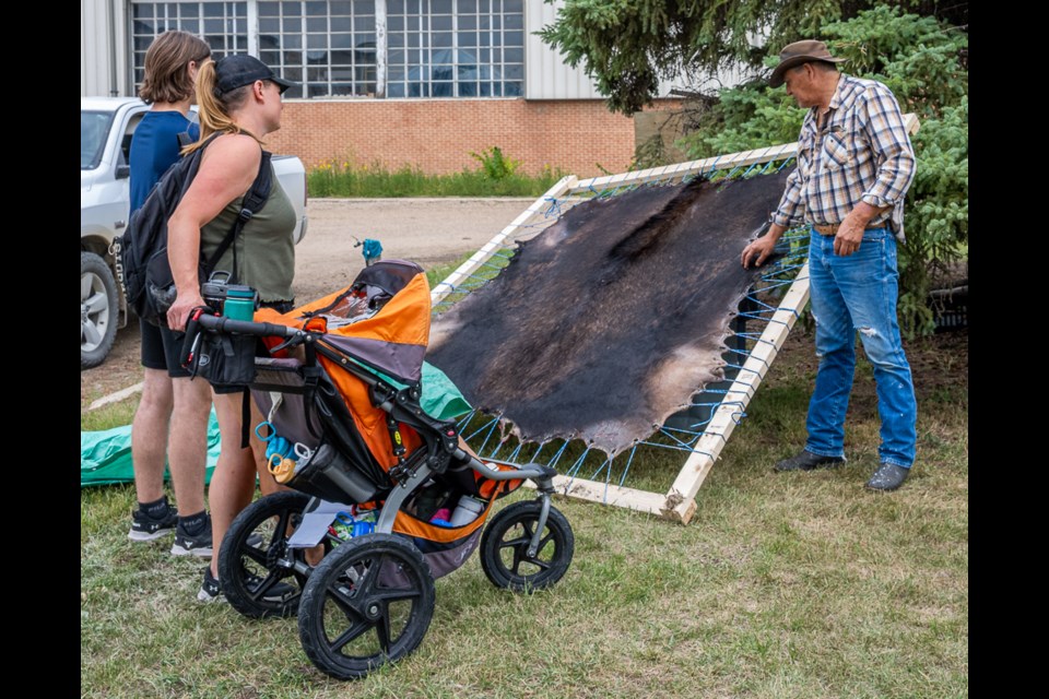 Fred Bill shows the stretched out moosehide with the hair side showing on a frame to visitors.