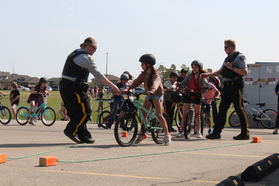 Constable Kimberly Flett of the Yorkton RCMP (left) helps a student navigate the obstacle course at the Grade 3 Bike Safety Rodeo.