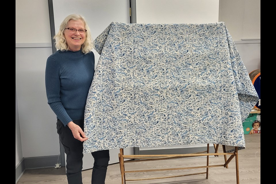 Bernadette Leslie posing with one of the Second World War quilts given to the Fred Light Museum.