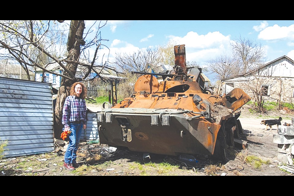 Cheryl stands beside a tank in a small town northwest of Kyiv that had been occupied by Russian forces for over a month