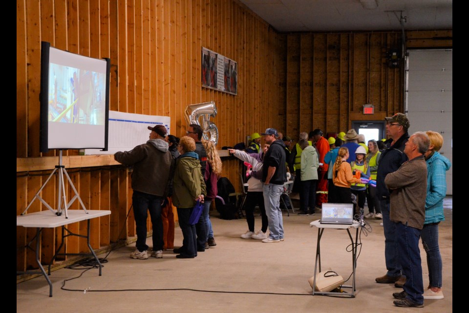 Compass Minerals employees, retirees and family members check out the slideshow and list of employees over the years, while in the background others put on PPE in preparation for a tour of the salt plant, May 30.
