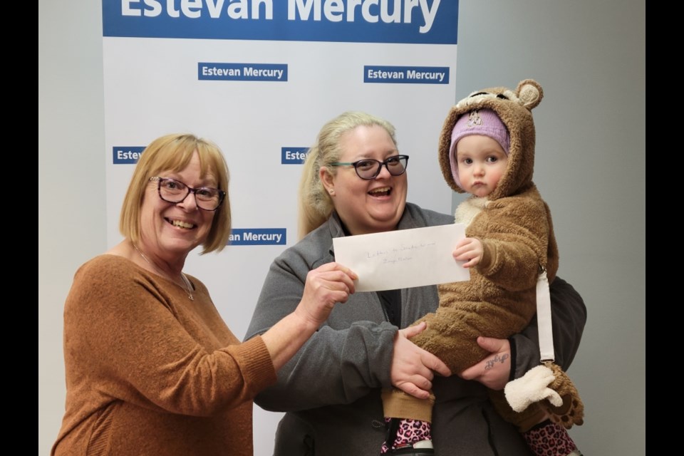 From left, Estevan Mercury sales manager Pat Pasloski presents the Letters to Santa prize to Terrie Nielsen and Zonya Nielsen. 