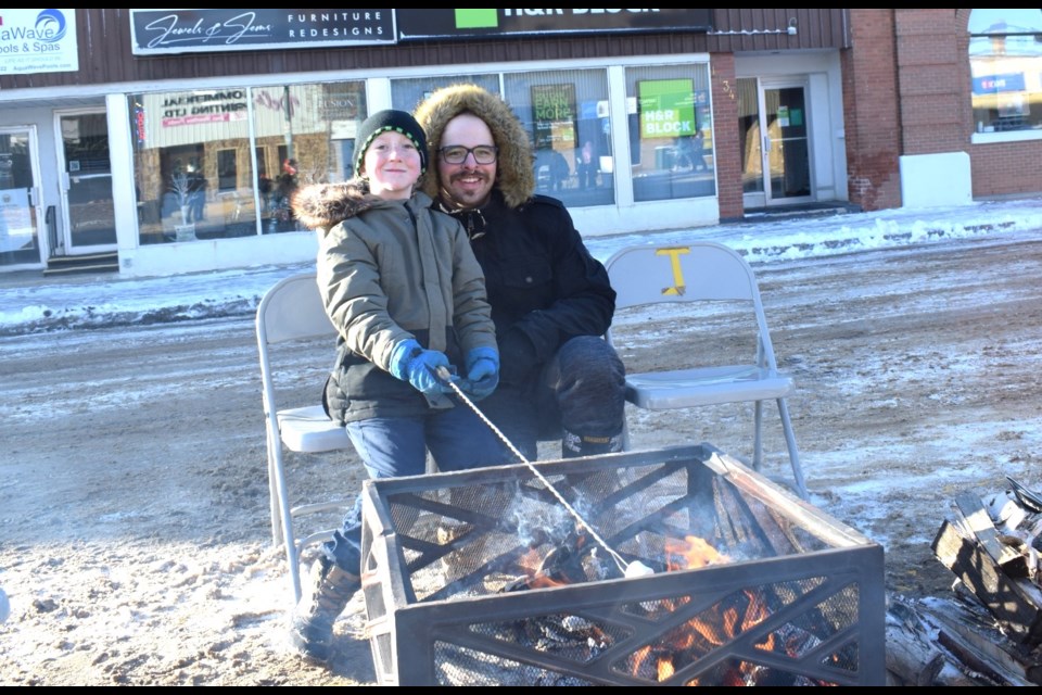 Damian Gervais, left, and Jesse Gervais cook marshmallows at a fire pit. 