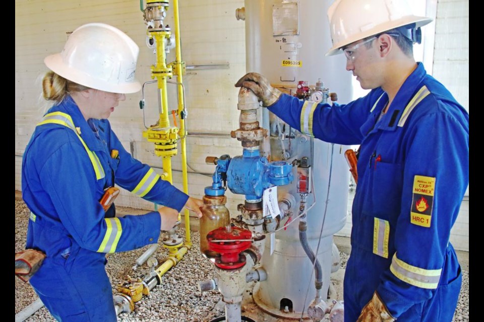 Mikaila Mahnke and Marcus Gregory set up to take an oil sample at a satellite production site on Friday. Both are engineering students working for the summer for Whitecap Resources out of their Goodwater plant.