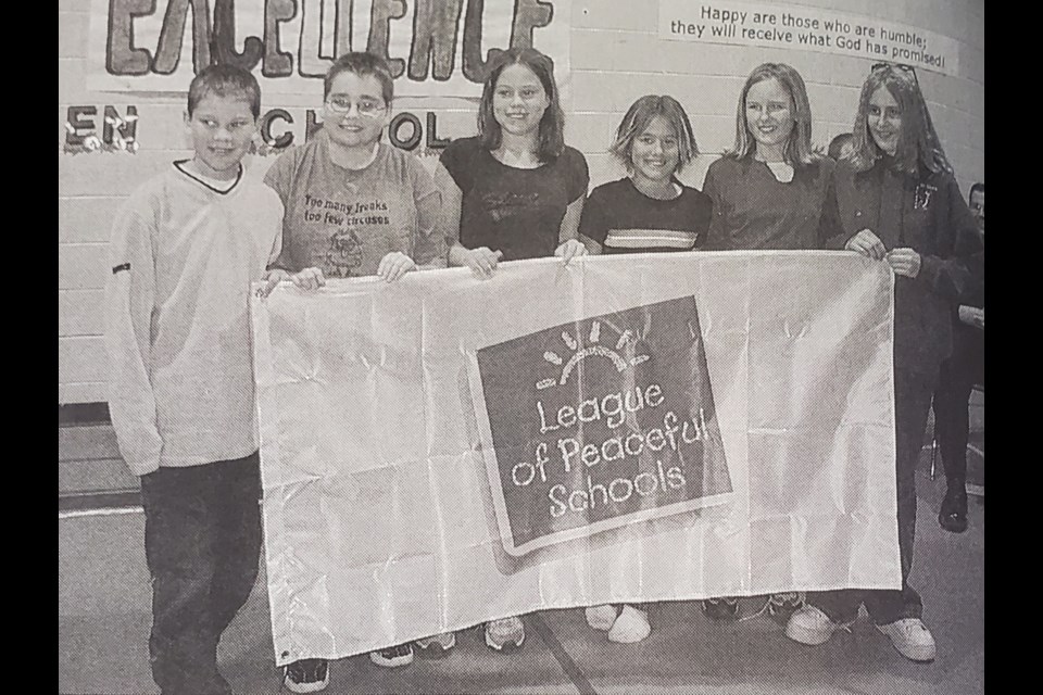 St. John’s School students hold up the flag the school was presented during the League of Peaceful Schools Assembly on Oct. 24, 2002. Holding the flag are Kaitlin Bill, Brittany Bjorndalen, Kayla Christofferson, Chandra Drabek, Joseph Huculak and Brett King.