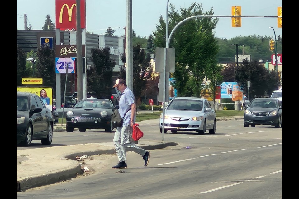 A pedestrian crosses 22nd Street, at risk due to oncoming traffic. 