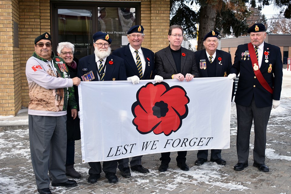 North Battleford Mayor David Gillian holds a poppy flag for Remembrance Day with members of the Legion before the flag is raised at City Hall.