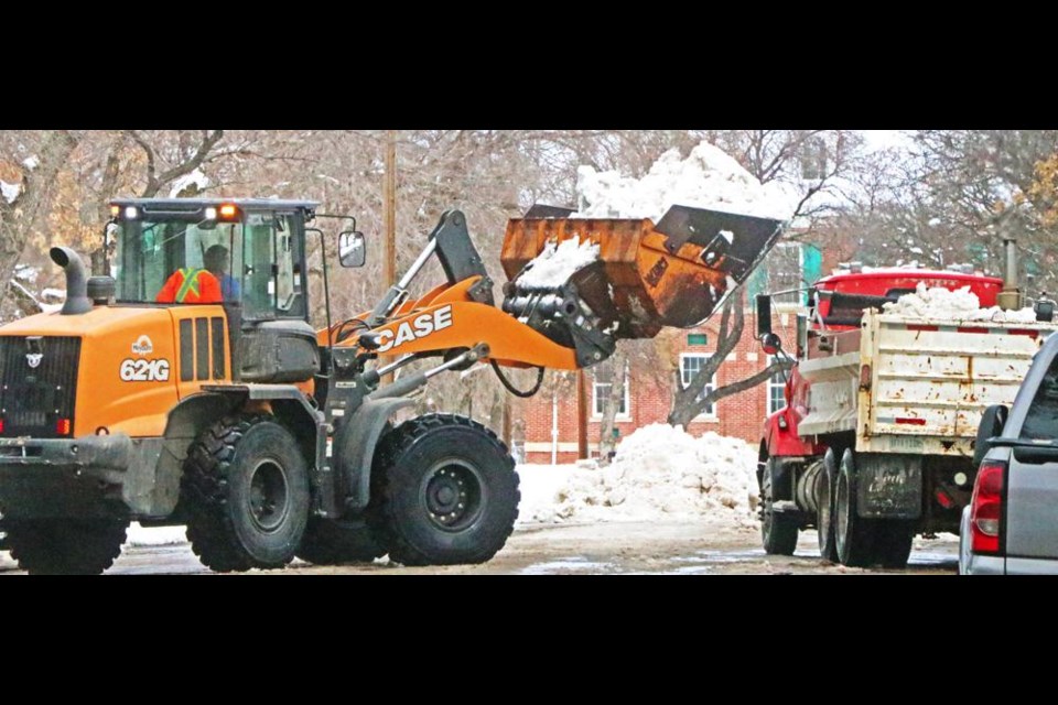 City crews were kept busy Friday removing large piles of heavy wet snow off the streets, starting from the downtown streets; this view is looking north on Third Street.