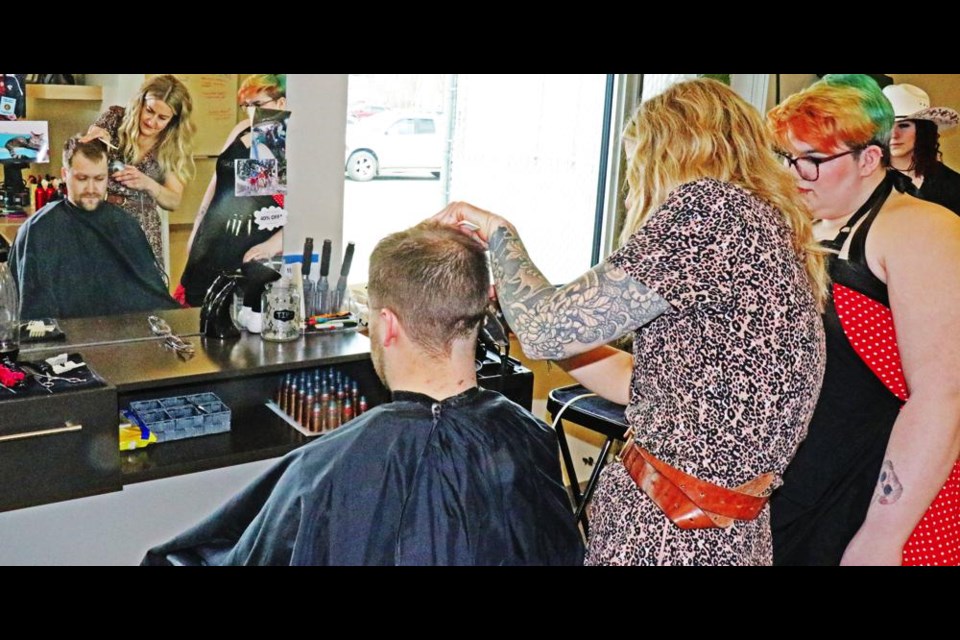 Sgt. Steven Cox of the Army Reserves got a haircut from SE College's teach-and-trim hairstylists salon during the college's open house, with instructor Kate Mahoney and student Chloe Drader