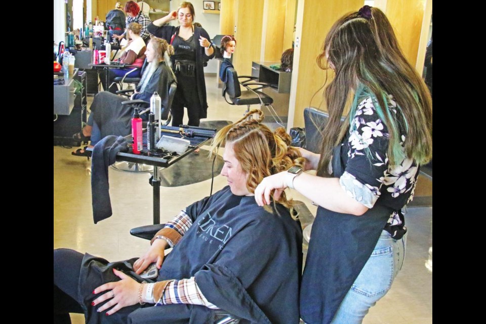 Stylist Bryanna Morrow, at right, worked on a hairstyle for Reegan Frey, as part of a grad hair-and-makeup competition on Saturday at SE College.
