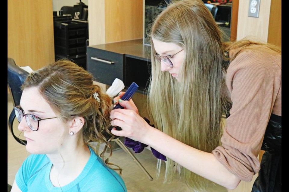 Julie-Anne Vogel, right, a hairstylist student, worked on the hair of her model, Dawson Fuller, in the hairstylists competition at SE College on Saturday