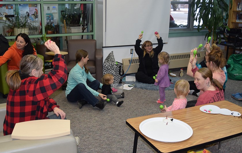 At the Kindermusik and Zumbini movement and early learning program in the Canora Library on Dec. 16, Kim Gelowitz, Regional Kids First Community Developer (centre, facing camera) led the youngsters and their parents in a number of activities. In the photo, the kids are learning movement and using their shakers in rhythm, holding them high in the air.