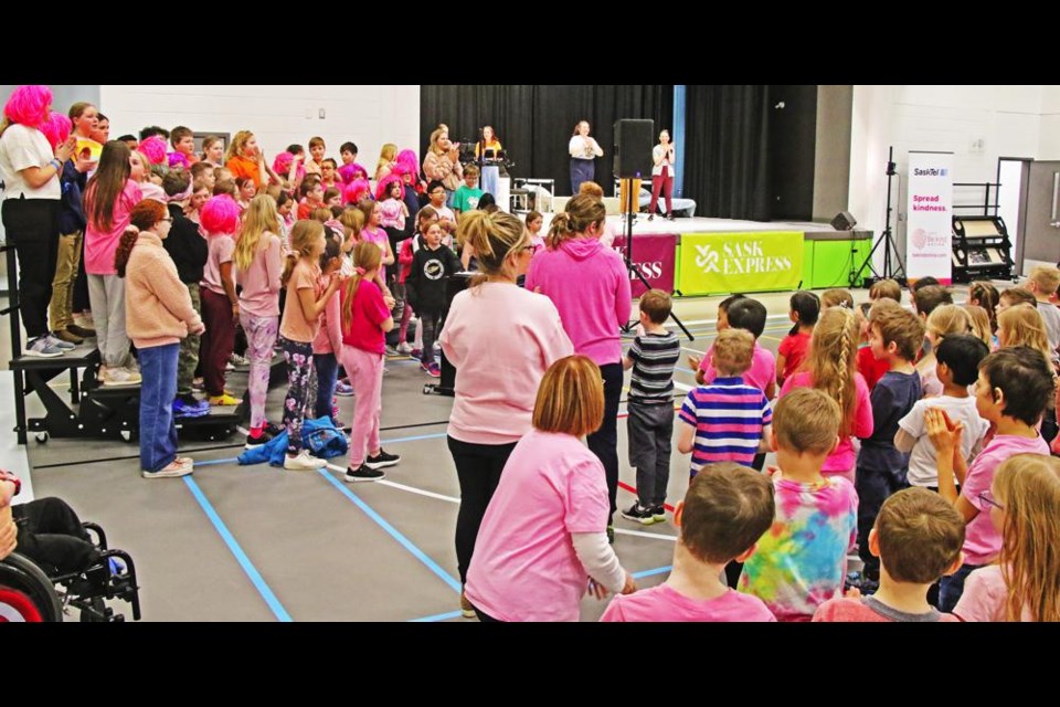 The cast of SaskExpress came on stage to listen as Legacy Park students sang the school's song for them, all wearing pink for Pink Shirt Day on March 1.