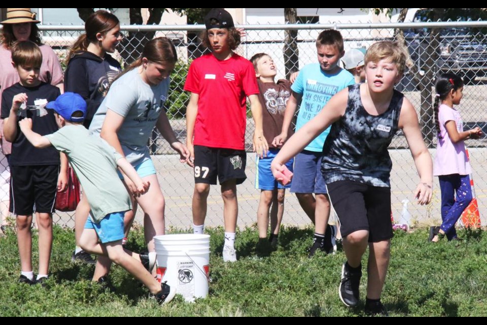 One of the relay races was for a line of students to squeeze water from a sponge into a pail, in a race against another team, at LPES's playday on Friday.