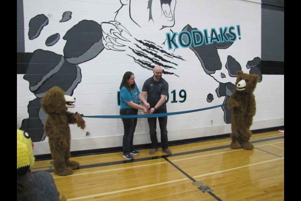 While the Kodiak bears held it, Vice-Principal Anneliese Hampson (left) and Principal Jeff Barrett cut the teal ribbon to mark the official grand opening of Cut Knife Community School.                           