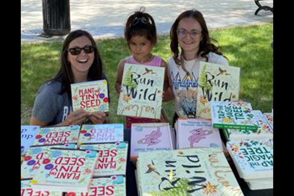 A Pre K student from Notre Dame School along with her mom and teacher celebrate some of the book titles available to choose from.