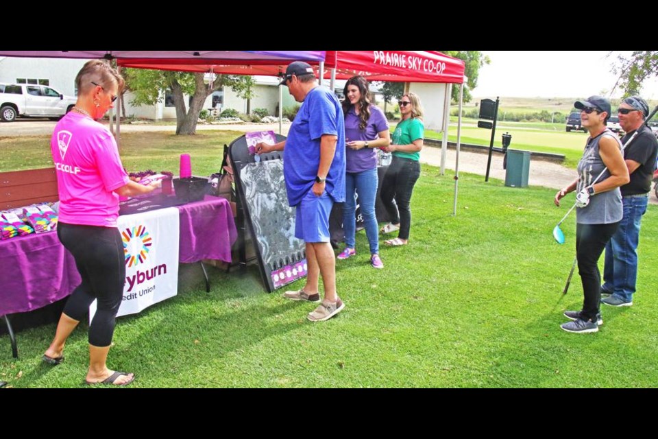 Laure Speers picked a prize as her husband Ernie played the Plinko game at the Weyburn Credit Union booth at the Swing for Scholarships golf tournament on Friday. The Speers, from Speers Contracting Ltd., were golfing with Nola and Rick Moffatt at right. Jasmine Kravanya of the Credit Union manned this booth, along with Danielle Knoll at the Prairie Sky Co-op booth, on the first hole for the fundraiser golf tourney.