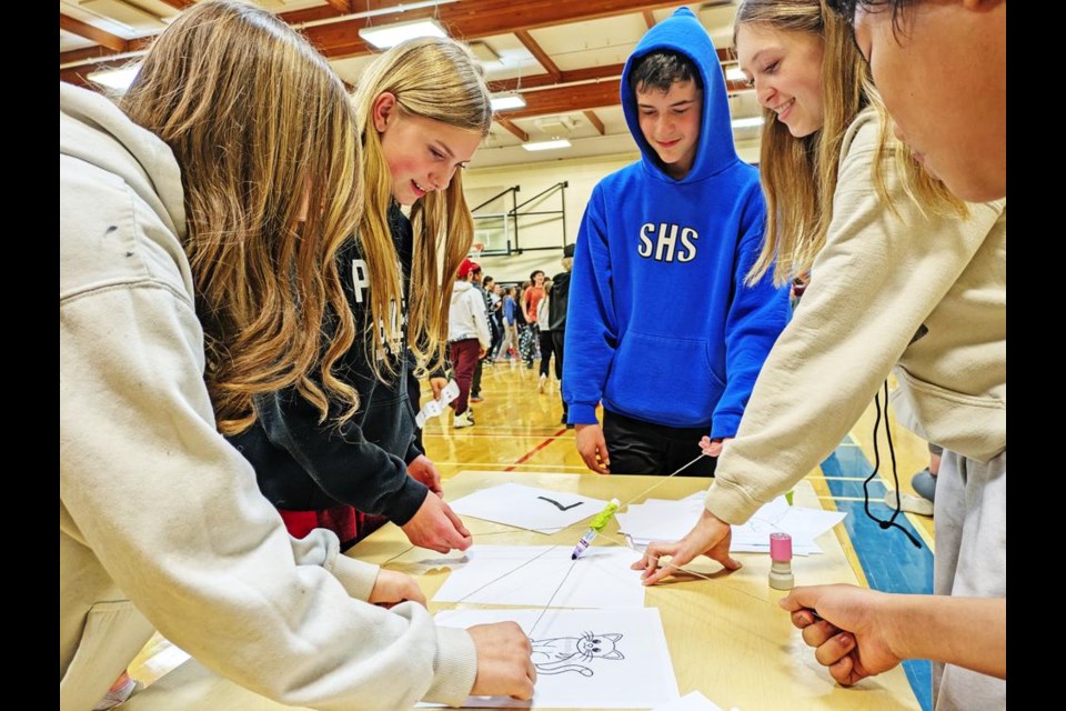 A team had to work together to make a marker attached by strings to make a picture in a minute's time.