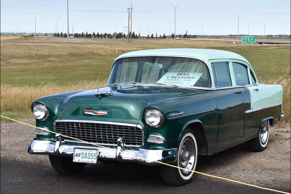 A 1955 Chevrolet Model 210 sits at the back of the parking lot.