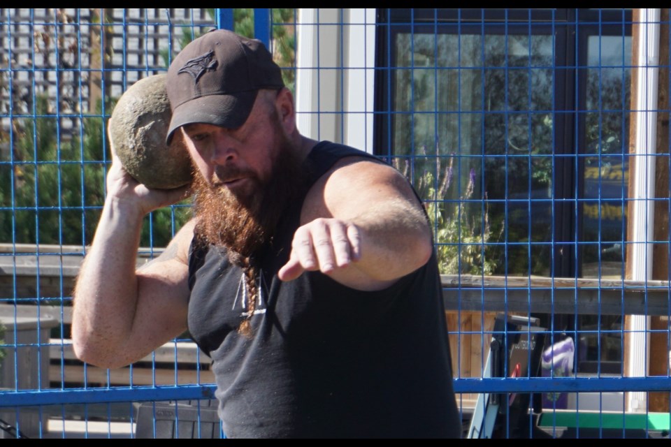 One of the male competitors concentrates on his attempt to throw the stone at the farthest distance. on