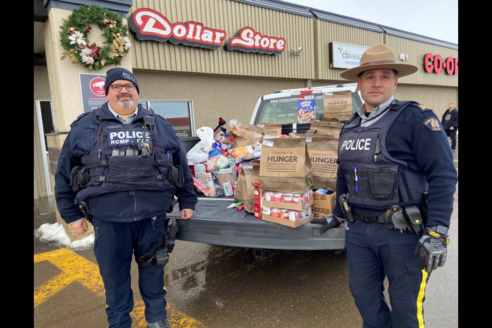 Battlefords RCMP Corporal Steve Bell, left, and Staff Sgt. Ryan How, right, with the Cram the Cruiser food drive in North Battleford Saturday.