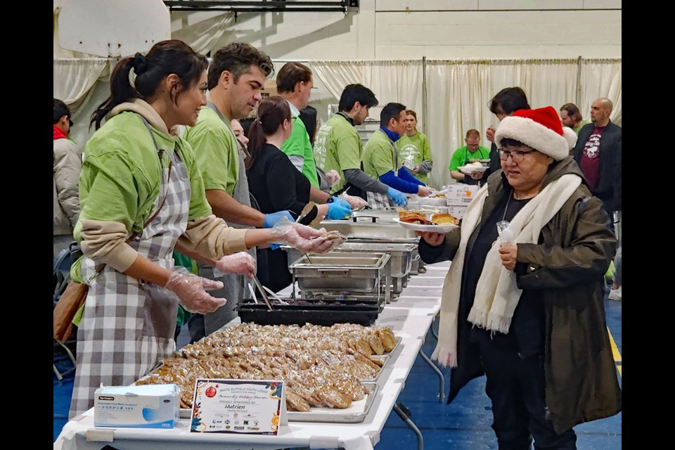 Volunteers serve a relative during the holiday dinner Thursday night, Dec. 15, at the White Buffalo Youth Lodge.