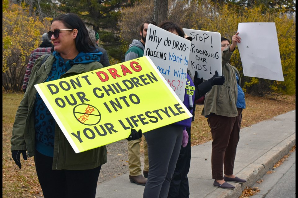 Members of the group hold various signs protesting the storytelling event done by drag performers.  