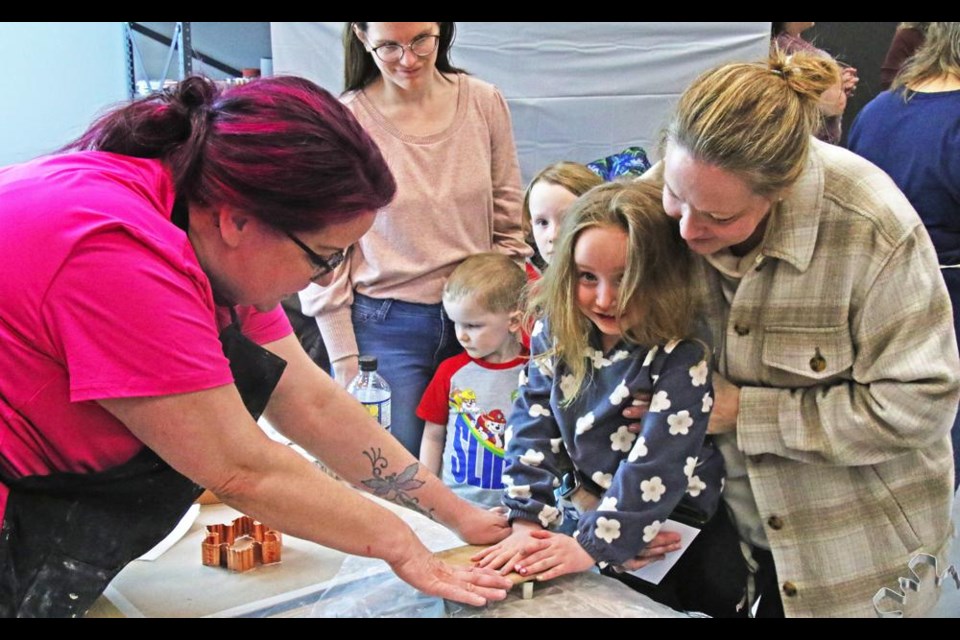 Arts council volunteer Elizabeth Lambe, left, helped to guide Seren Harvey and her mom Cathy make a clay shape, which they could then paint with a glaze colour of their choice, on Family Day.