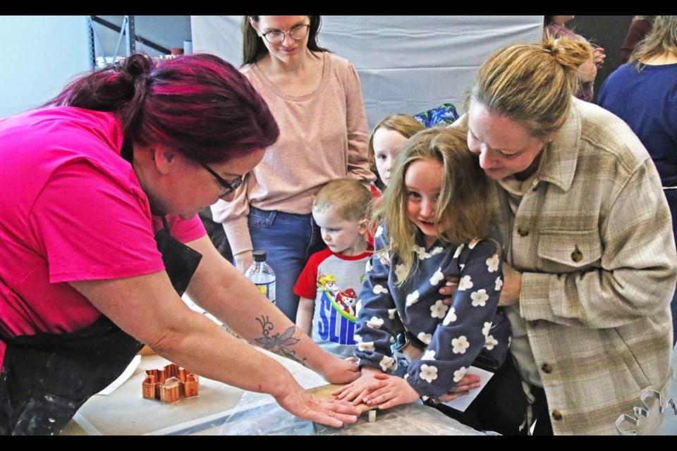 Arts council volunteer Elizabeth Lambe, left, helped to guide Seren Harvey and her mom Cathy make a clay shape, which they could then paint with a glaze colour of their choice, on Family Day.