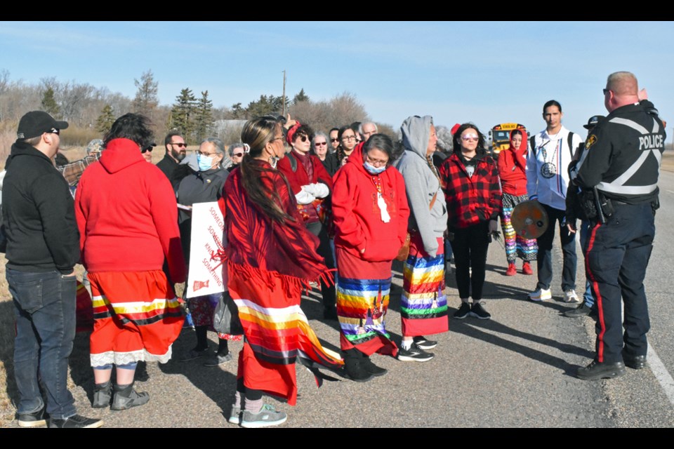 A police officer, right, gives instructions to the group before beginning the walk toward the City of Saskatoon.