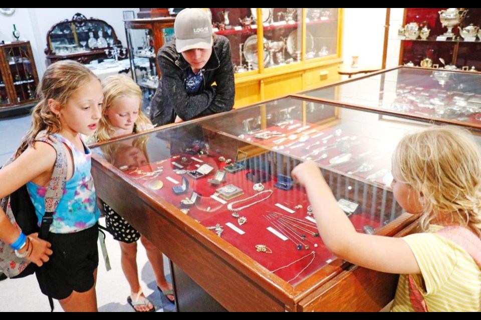 A group of girls have a close look at jewelry on display in the Charlie Wilson Silver Collection, during a visit to the Soo Line Museum by the participants in the Fun in the Sun summer rec program on Thursday.